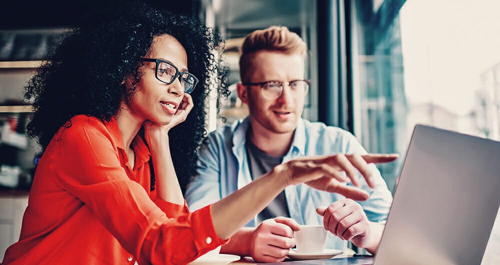 Man and woman looking at search analytics on a computer to review website's success.