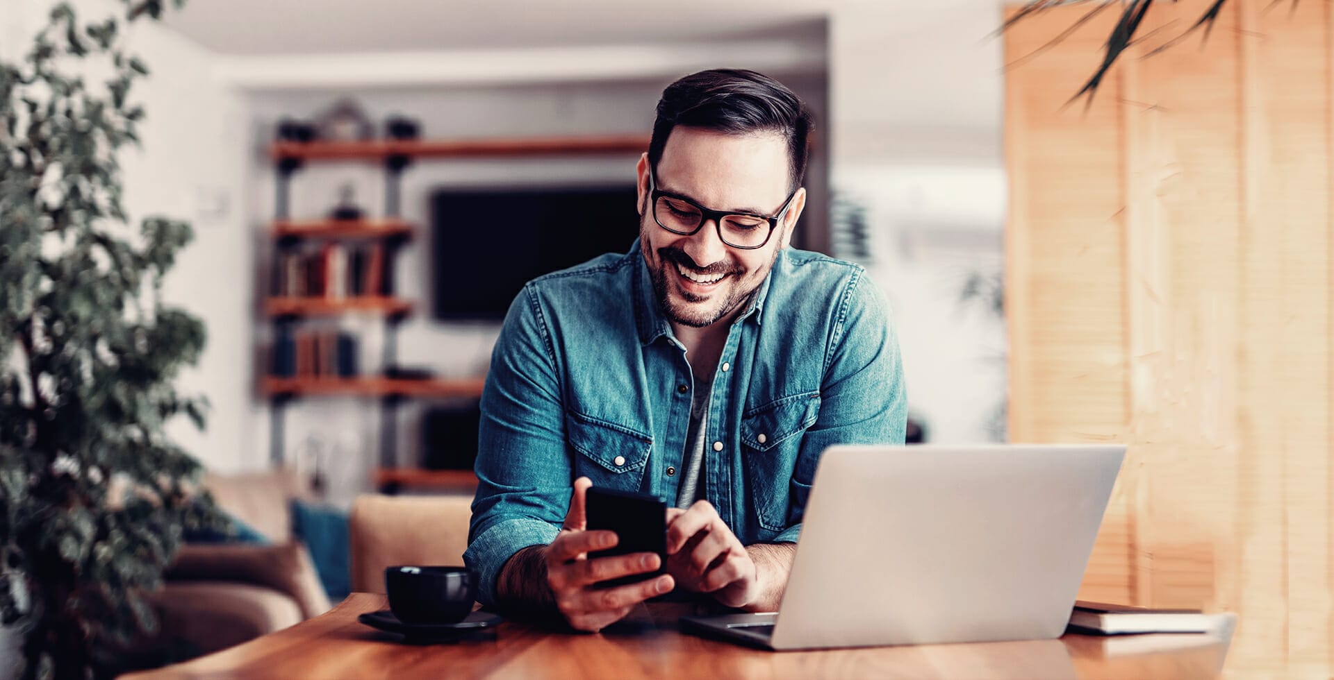 Man with glasses smiling at his phone while searching a retail site for products.